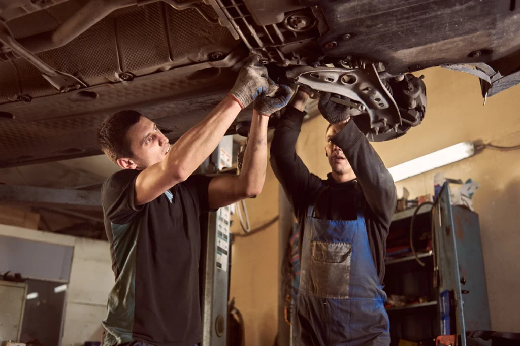 two mechanics working underneath a vehicle